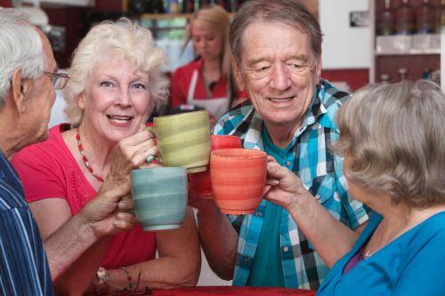 Smiling,Woman,With,Senior,Friends,Toasting,With,Coffee,Mugs